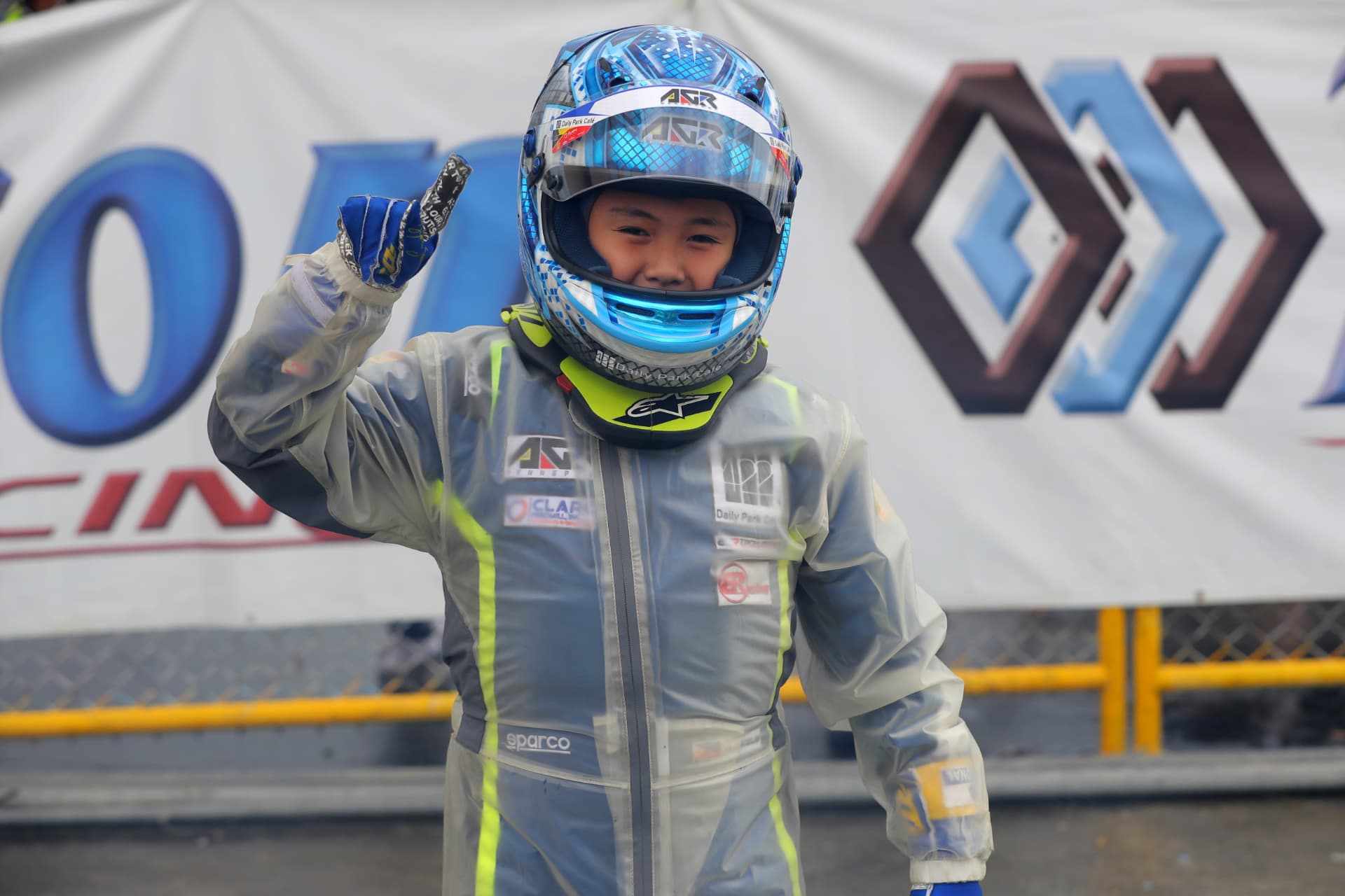 Antonio Racelis in a rain suit, waving after the race