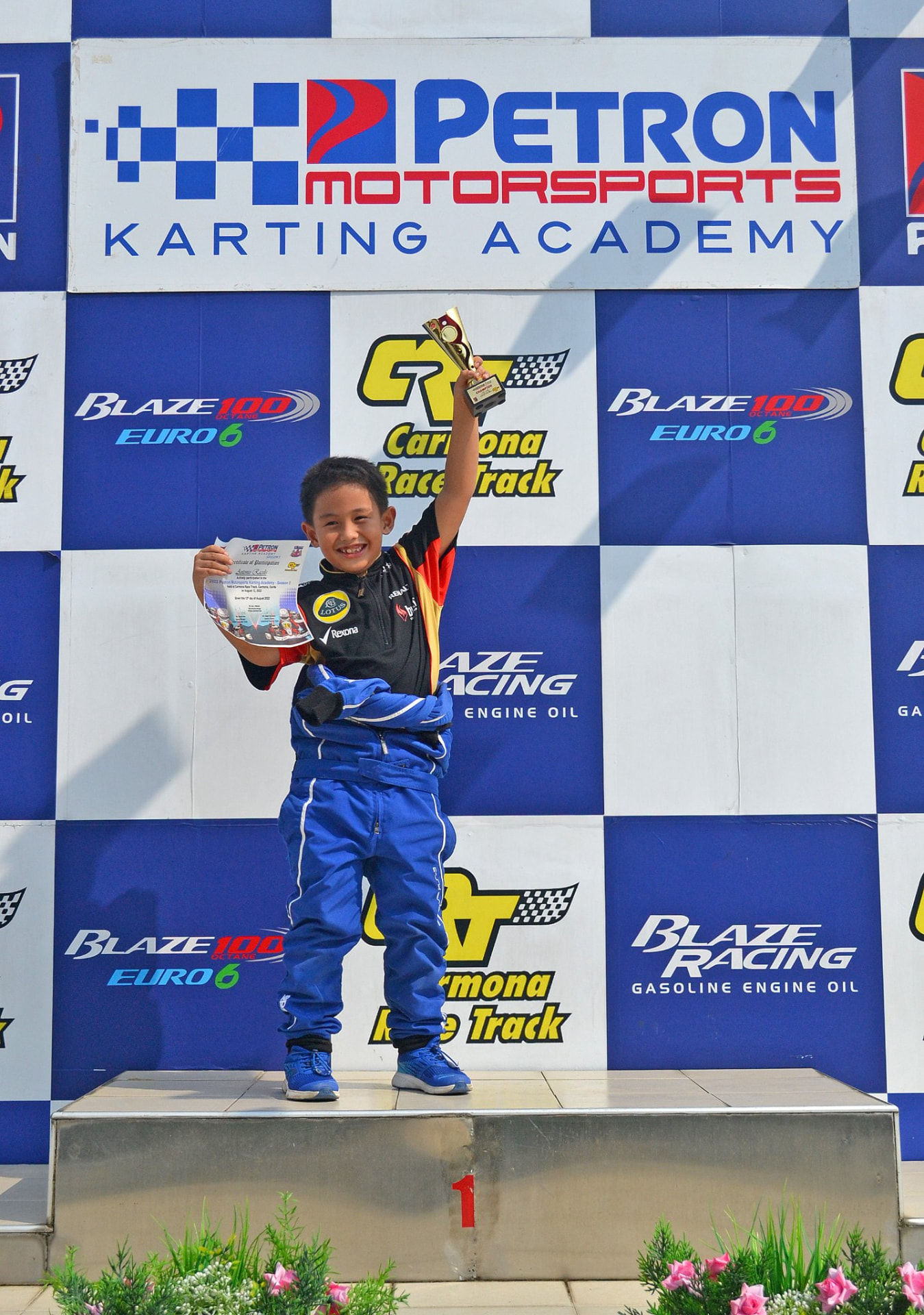 Young Antonio Racelis lifting a trophy on the karting academy podium